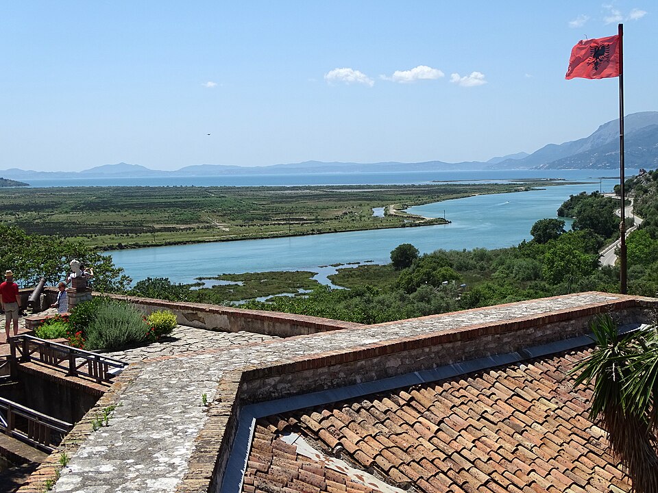 Ruins at Butrint National Park in Albania, with stone structures surrounded by greenery and distant hills.
