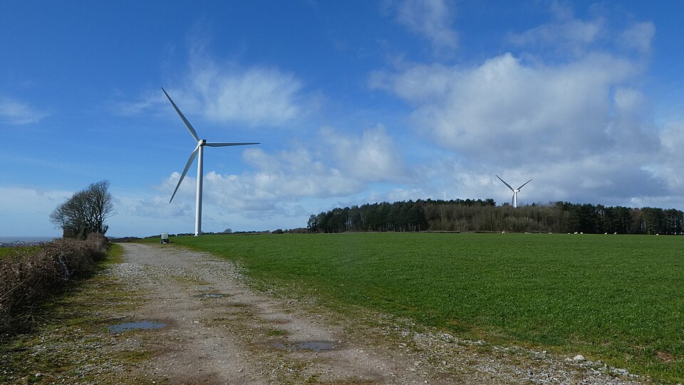 Two wind turbines standing on open land near Tythegston, with grassy fields.