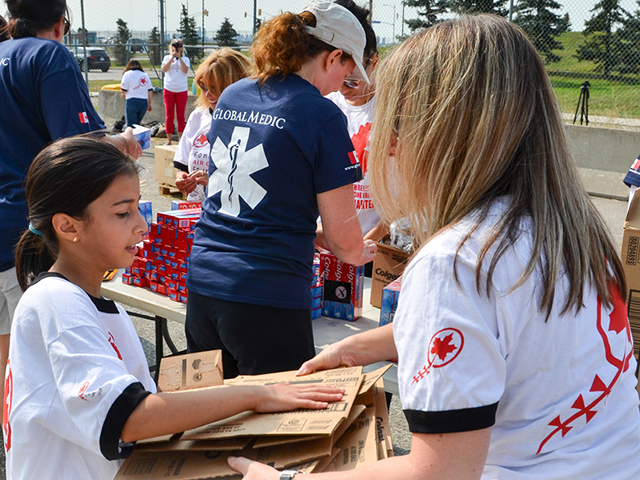 A girl volunteer offers a child some cardboard packages during a humanitarian campaign