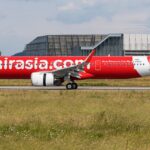 AirAsia A320 aircraft landing on the runway, surrounded by grass