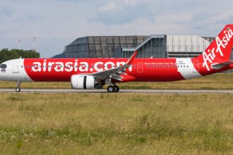 AirAsia A320 aircraft landing on the runway, surrounded by grass
