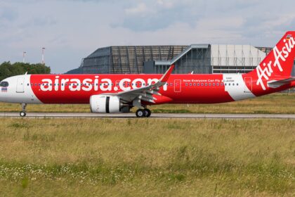 AirAsia A320 aircraft landing on the runway, surrounded by grass