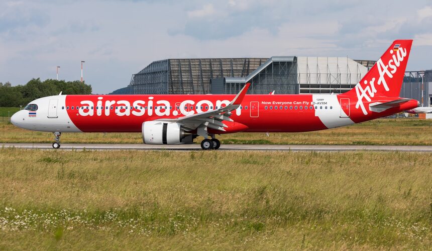 AirAsia A320 aircraft landing on the runway, surrounded by grass