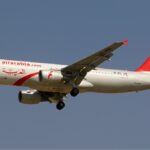 Air Arabia Airbus A320 flying toward the left side. Grey sky in the background. White and red livery.