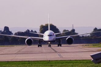 British Airways aircraft at London Heathrow Airport, on the runway before takeoff, heading towards the camera. Trees in the background.