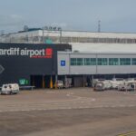 Exterior view of Cardiff Airport, terminal building. Ground vehicles outside near the apron.