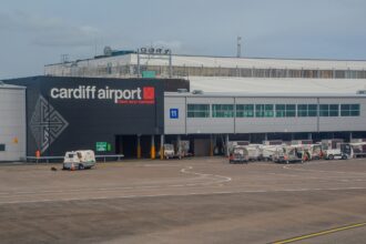 Exterior view of Cardiff Airport, terminal building. Ground vehicles outside near the apron.