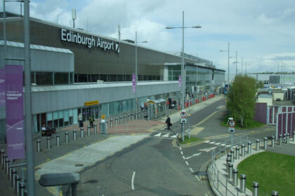 Edinburgh Airport terminal building with drop-off lanes, pedestrians, and transport access outside the entrance.