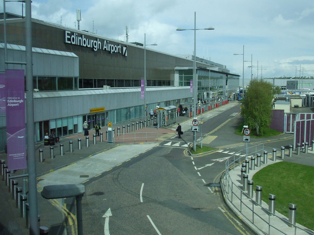 Edinburgh Airport terminal building with drop-off lanes, pedestrians, and transport access outside the entrance.