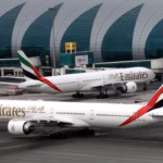 Emirates Airline Boeing 777-300ER aircraft at Dubai International Airport, one facing forward and one staying on the left