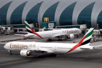 Emirates Airline Boeing 777-300ER aircraft at Dubai International Airport, one facing forward and one staying on the left