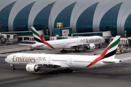 Emirates Airline Boeing 777-300ER aircraft at Dubai International Airport, one facing forward and one staying on the left