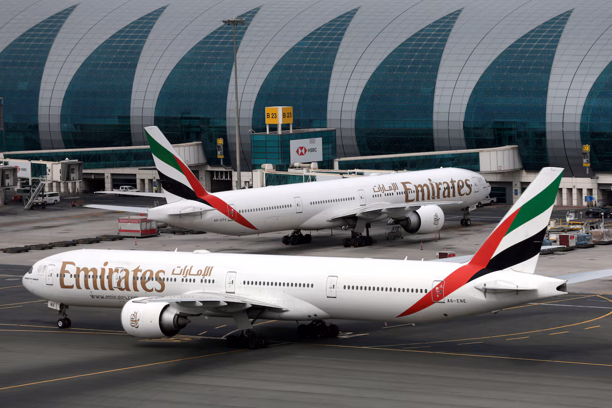 Emirates Airline Boeing 777-300ER aircraft at Dubai International Airport, one facing forward and one staying on the left.