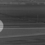 Grayscale surveillance-style image from Denver International Airport showing a man highlighted with a circle walking across a runway