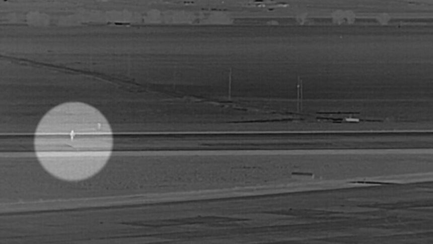 Grayscale surveillance-style image from Denver International Airport showing a man highlighted with a circle walking across a runway