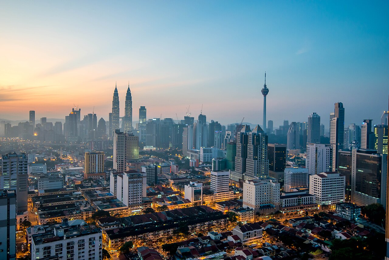 Kuala Lumpur skyline at dawn featuring various skyscrapers and the lights of the city.