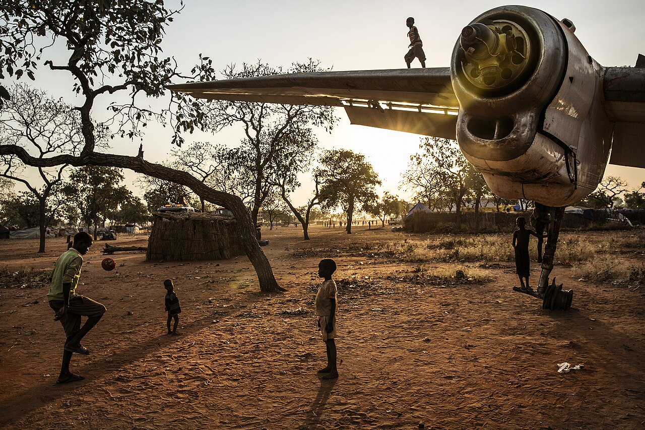 Children playing with a ball, another child on the wreck of an Antonov Transport plane.