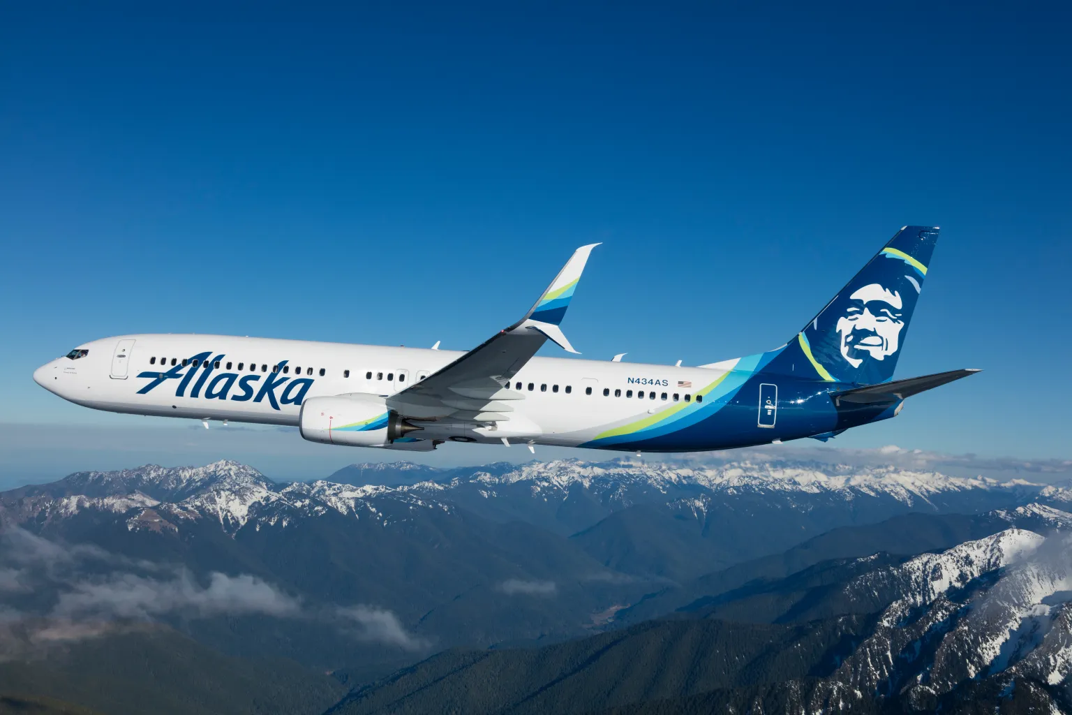 Alaska Airlines Boeing 737 in flight over snow topped mountains 