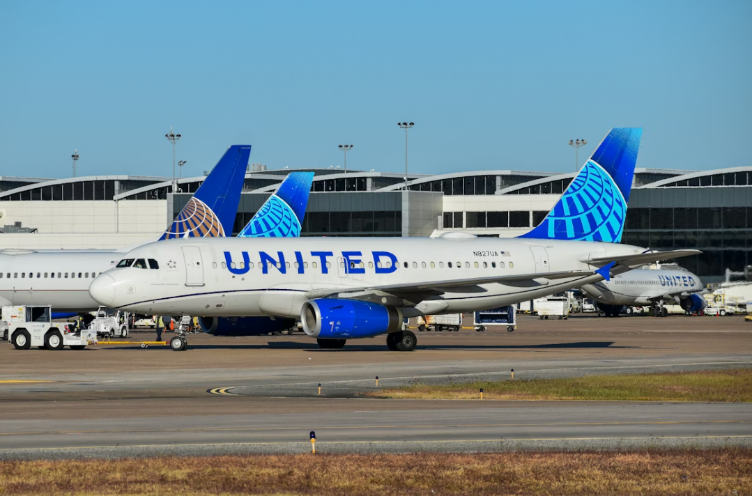 A large blue and white United Airlines jetliner sitting at an airport