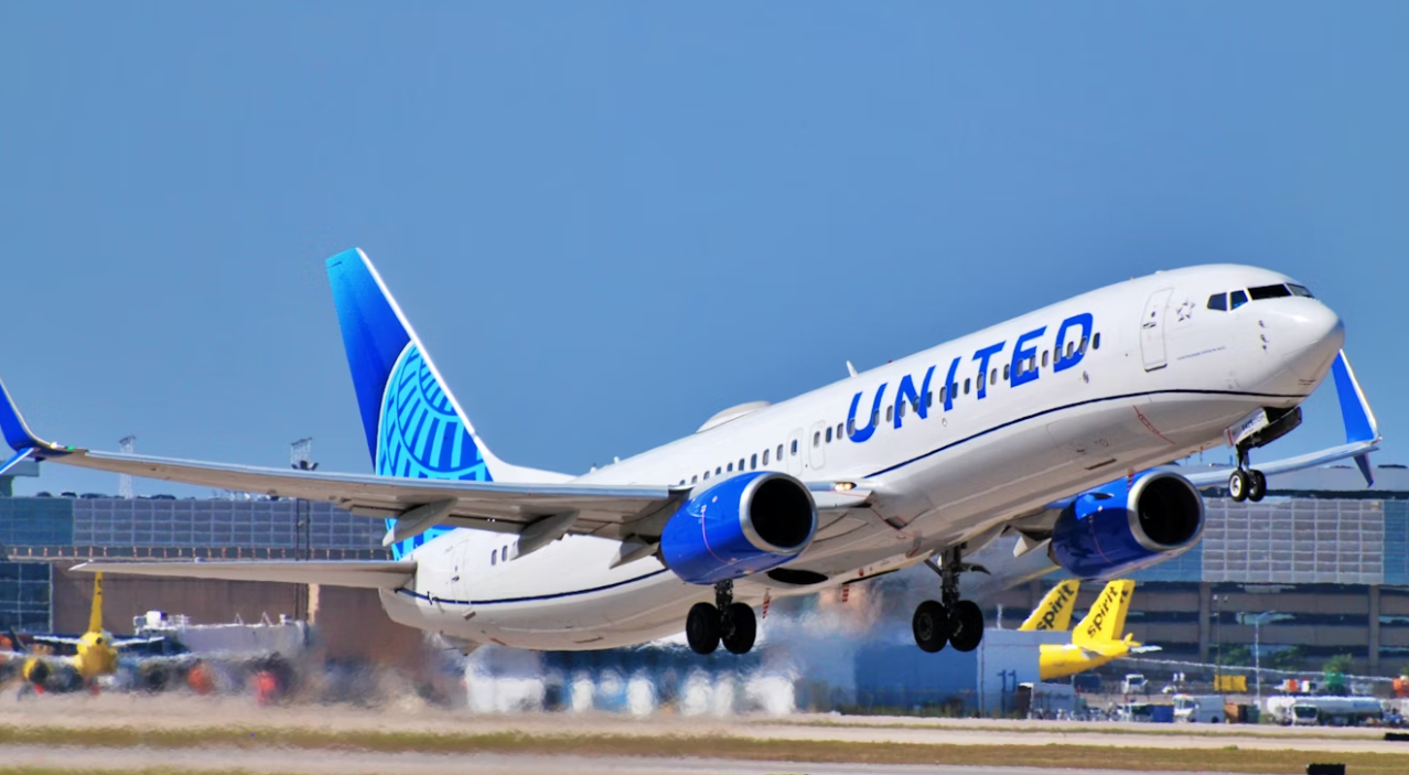 A large blue and white jetliner taking off from an airport runway