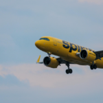 A large yellow jetliner flying in a blue sky