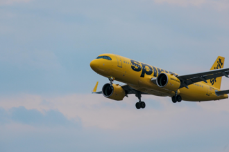 A large yellow jetliner flying in a blue sky
