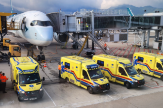 A large white jetliner sitting on a runway with four ambulances in front of it
