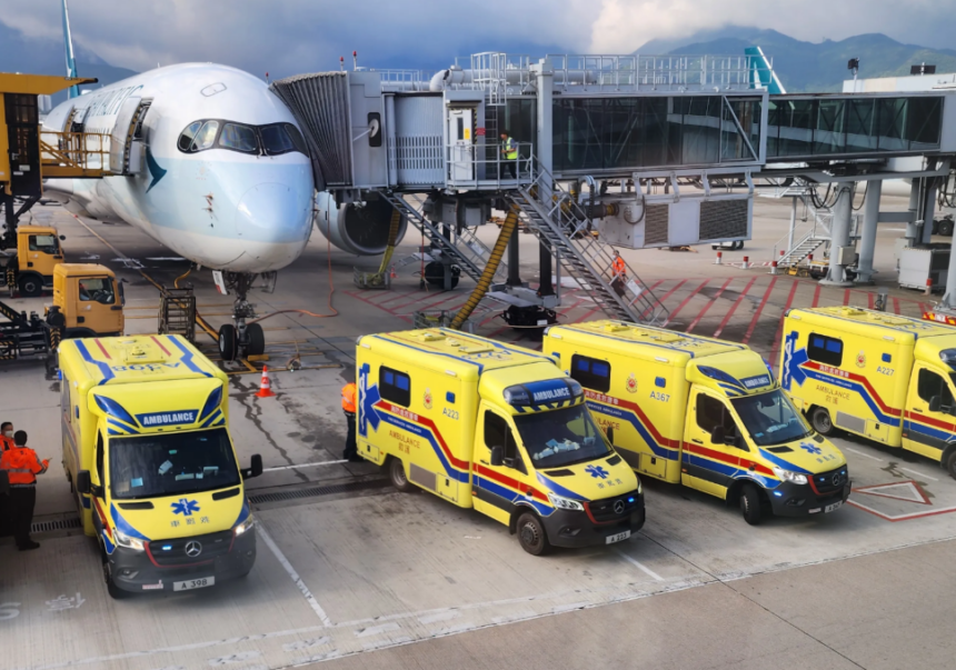A large white jetliner sitting on a runway with four ambulances in front of it