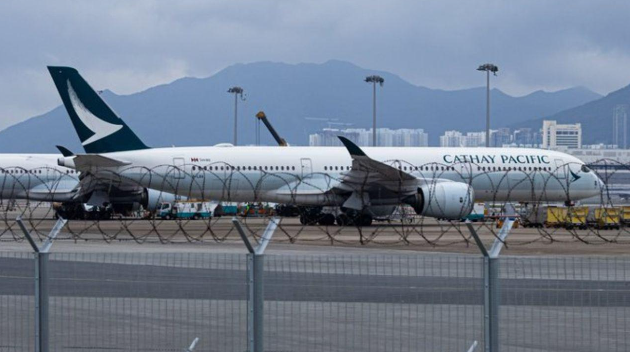 A large white jetliner sitting on an airport runway with mountains in the background
