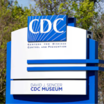 A large blue and white sign for the Centres for Disease Control and Prevention, with trees in the background