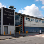 A grey and white building entrance with a large sign reading 'Welcome to East Midlands Airport'