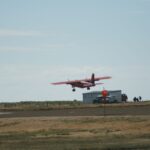 FIGAS plane flying over runway, low over grass