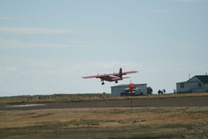 FIGAS plane flying over runway, low over grass