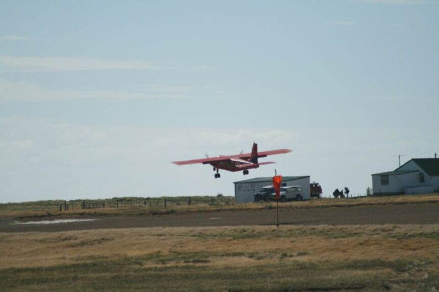 FIGAS plane flying over runway, low over grass