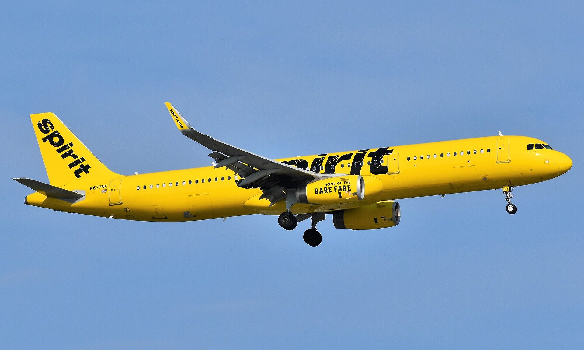 Spirit Airlines Airbus, flying through the blue sky towards the right side. Yellow and black livery.
