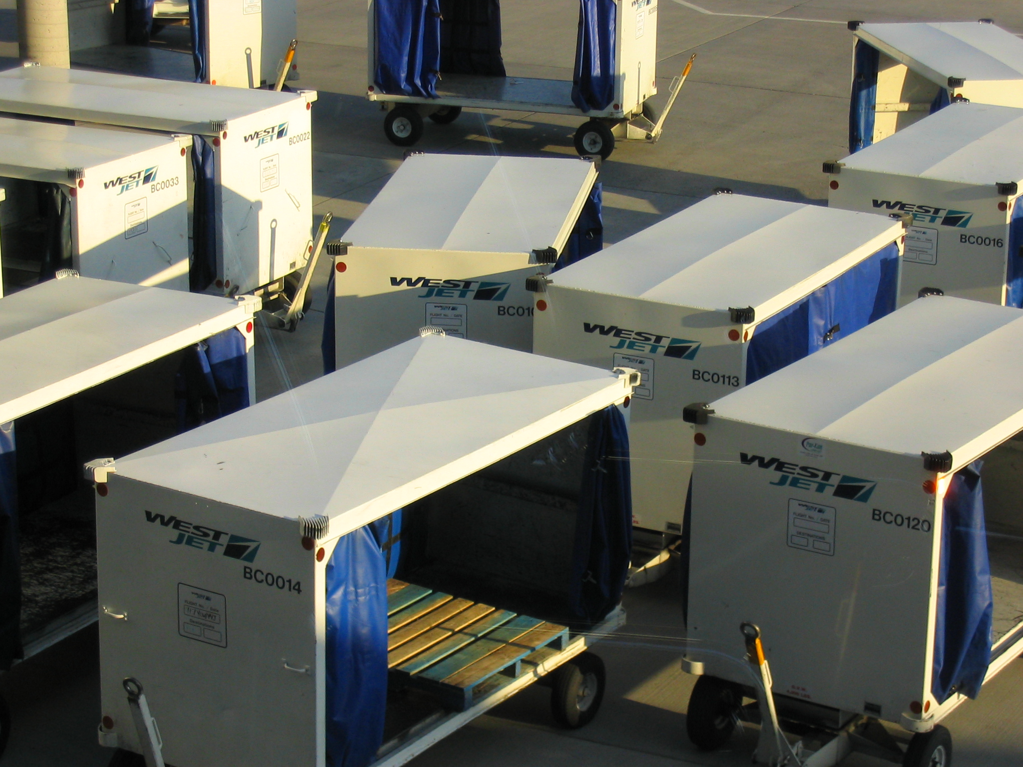Dozens of Westjet empty cargo bins on the tarmac at Calgary International Airport
