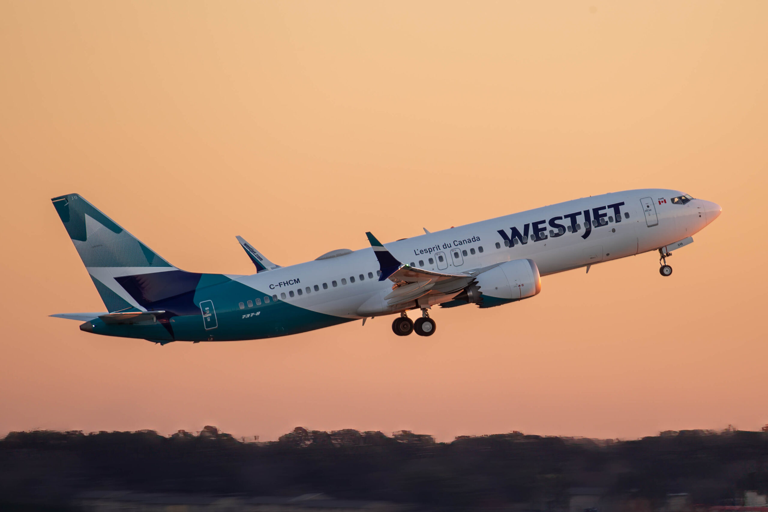 A WestJet Boeing 737 MAX taking off into the sky at sunset