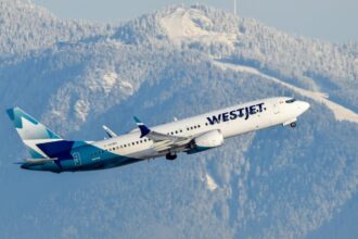 On a background of snowy mountains, a WestJet aircraft takes off into the sky,