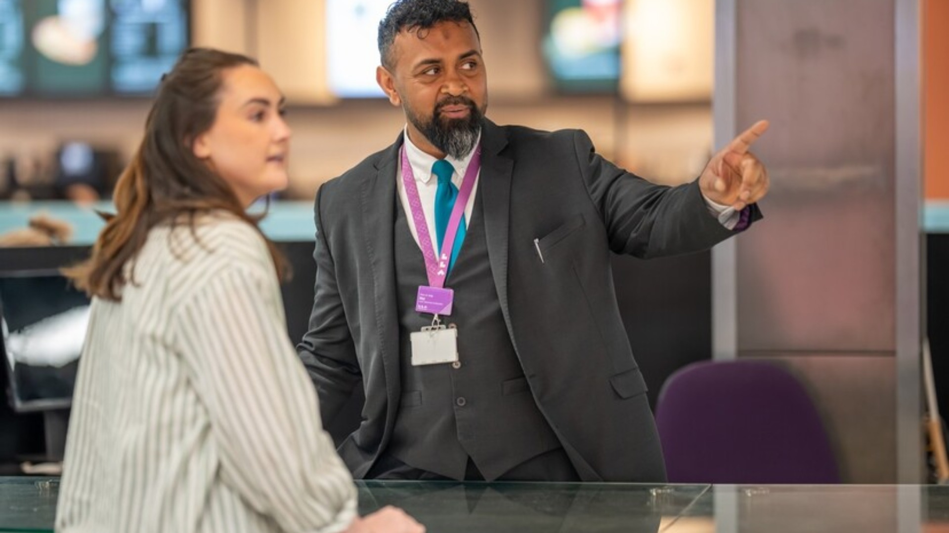 A male LLA worker points a female customer in the right direction, to the right.
