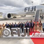 Several people behind a Fiji Airways sign and in front of an A350. There is a red carpet that leads to the aircraft.