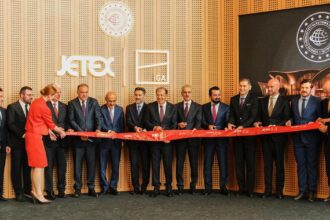 Jetex-Istanbul collaboration, colleagues standing in a line holding up a long sash. Men in suits and two women in red airline attire.