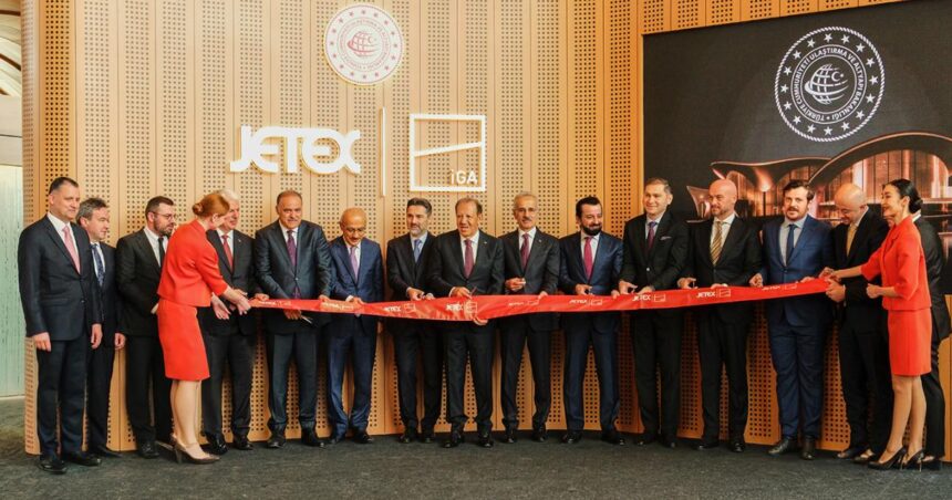 Jetex-Istanbul collaboration, colleagues standing in a line holding up a long sash. Men in suits and two women in red airline attire.