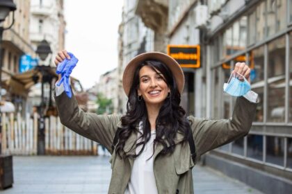 A traveller holding a used face mask and gloves in her hands in a town