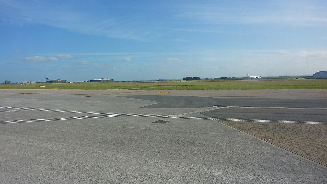 Newquay airport showing the airport apron with clear blue skies in the background and green grass.