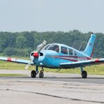 Image shows a small blue aircraft (Piper PA-28-151 Cherokee Warrior N405DS) grounded at Delaware Airpark during the day.