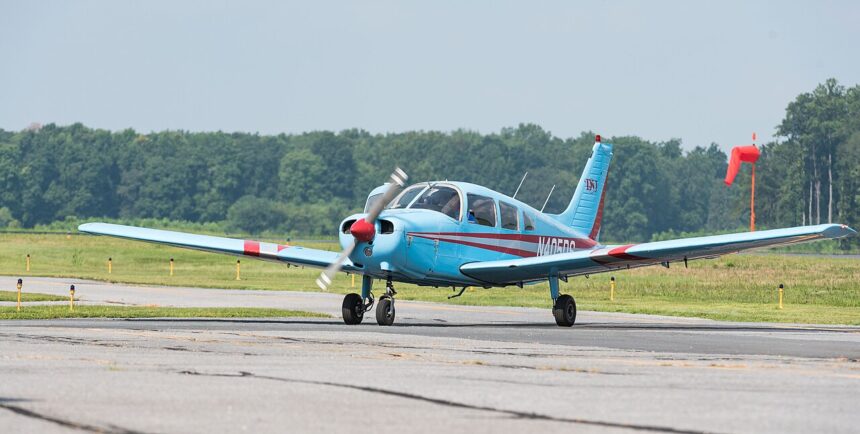 Image shows a small blue aircraft (Piper PA-28-151 Cherokee Warrior N405DS) grounded at Delaware Airpark during the day.