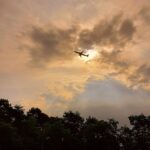 Plane in flight taking off from Malpensa International Airport in clear conditions with the sun setting.
