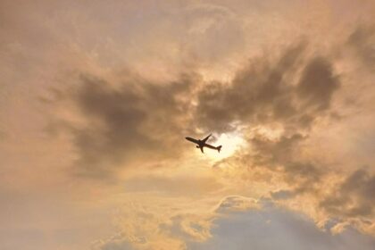Plane in flight taking off from Malpensa International Airport in clear conditions with the sun setting.
