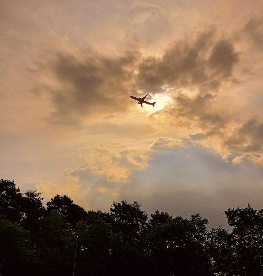 Plane in flight taking off from Malpensa International Airport in clear conditions with the sun setting.