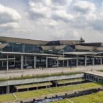 The outside of São Paulo International Airport (GRU) terminal 3, the international departure terminal. The sky is cloudy and the building is mostly grey but covered by windows.